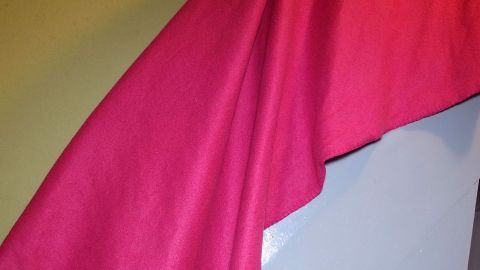 Ein pinkfarbener Stoff hängt an der Wand und verleiht dem Raum eine frische und einladende Atmosphäre.