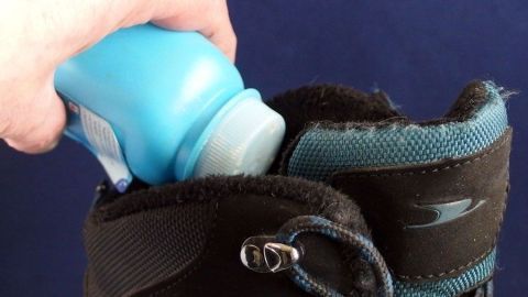Gegen müffelnde Schuhe und auch Füße hilft supergut Babypuder, einfach in die Schuhe streuen oder direkt auf die Füße. Ein Hand greift nach einem Babypulverbehälter und streut ihn in einen schwarzen Schuh, um Schuh- und Fußmief zu beseitigen.