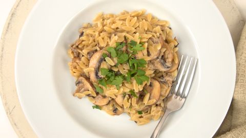 Genieße ein cremiges Risoni-Risotto mit Pilzen: Perfekt für ein schnelles, leckeres Gericht. Frische Kräuter als Garnitur runden es ab.