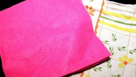 Ein pinkes und ein gemustertes Küchen Wischtuch liegen nebeneinander auf einem dunklen Untergrund, bereit zum Einsatz.