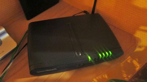 Ein WLAN-Router steht auf einem Tisch und leuchtet grün, während er in einer häuslichen Umgebung eine Verbindung bereitstellt.