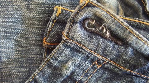 Alte Jeans liegen dekorativ übereinander, die Abnutzungsspuren zeigen ihre Geschichte und laden zur kreativen Verwertung ein.