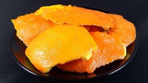 Orange Schalen liegen auf einem schwarzen Teller, bereit, als natürlicher Reiniger mit Essig verwendet zu werden.