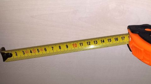 Ein Maßband wird ausgezogen, um Maße zu nehmen, in einem hellen, neutralen Raum. Ein Hinweis auf Abnehmen ohne Waage.