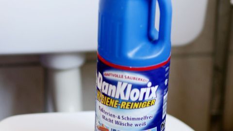Eine Flasche DanKlorix-Reiniger steht auf einer weißen Toilettenschüssel, bereit zum Reinigen der Toilette.