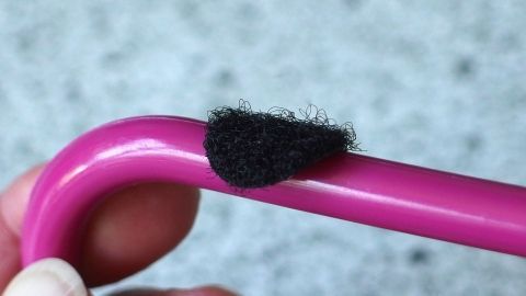 Ein rosa Bügel mit einem schwarzen, rutschfesten Überzug verhindert, dass Träger vom Bügel rutschen.
