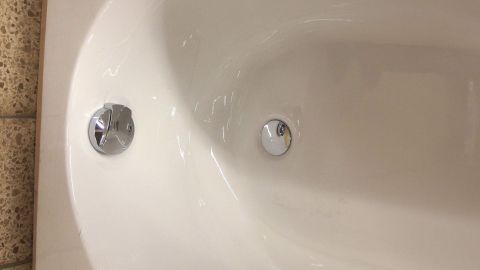 In einer Duschwanne sind zwei Abflussöffnungen sichtbar, während Wasser stagniert, was auf einen verstopften Abfluss hindeutet.