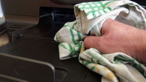 Ein Handtuch aus Kochwäsche wird fest in einer Hand gehalten, während es eine Oberfläche abwischt, in einer sauberen Küche.
