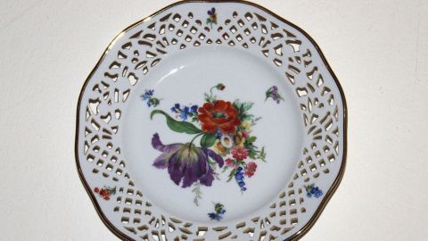 Ein dekorativer Teller mit Blumendekor hängt an einer Wand, um den Raum mit einem charmanten Accessoire zu verschönern.