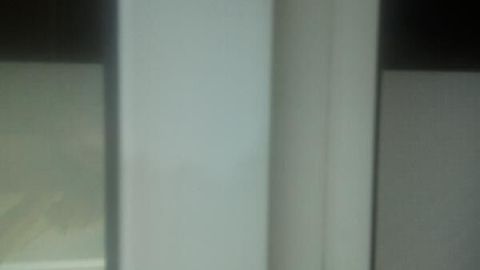 Ein Kunststoff-Fensterrahmen steht im Fokus, mit sichtbaren Schmutz- und Fleckenresten, die Reinigung benötigt.