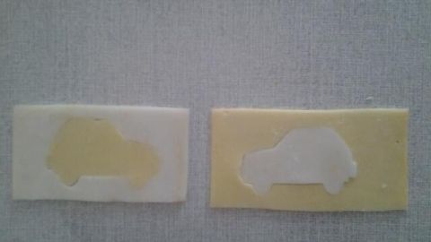 Zwei Stücke abgewandelter Käse zeigen Autoschablonen, die kreativ für ein Kinderbuffet gestaltet sind.