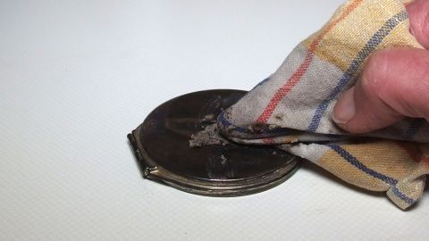 Schmuck günstig und effektiv mit Asche reinigen - auch die hartnäckigsten Flecken verschwinden. Ein Handtuch reinigt Asche von einem Schmuckstück auf einer weißen Oberfläche, um den Schmuck günstig und effektiv zu säubern.