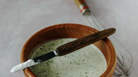 Eine Schale mit geronnener Sauce steht auf einem Tisch, während ein Messer und ein Schneebesen daneben liegen.