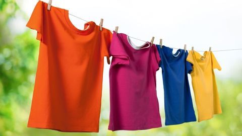 Bunte T-Shirts hängen frisch gewaschen an einer Wäscheleine im Freien, ideal zum Entfernen von Schweißgeruch.
