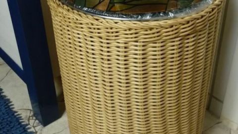 Ein stilvoller Badezimmer-Mülleimer mit einem geflochtenen Korb und einem schönen, farbigen Deckel steht neben einem blauen Teppich.