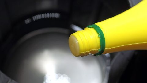 Eine gelbe Flasche gießt eine Reinigungslösung in einen Wasserkocher, um Kalk im Wasserkocher zu vermeiden.