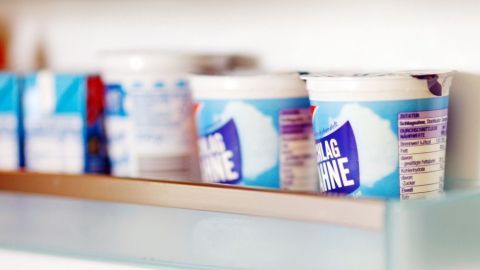 Im Kühlschrank stehen offene Sahnebecher, die ordentlich auf einem Regal platziert sind.