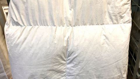 Ein Federbett wird in einer Waschmaschine gewaschen, um es sauber und frisch zu halten. Die Umgebung ist eine Waschküche.