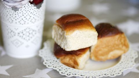 Käsebrötchen stehen auf einem filigranen Teller, umgeben von einer blütenförmigen Vase mit Rosen und einem hellen Hintergrund.