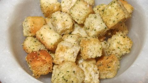 Herzhafte Brotwürfel liegen in einer Schüssel und warten darauf, als Snack anstelle von Chips genossen zu werden.