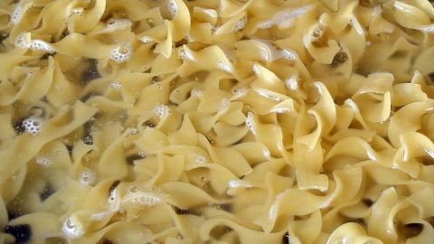 Nudeln schwimmen im kochenden Wasser und garen gleichmäßig in einem Topf auf dem Herd.