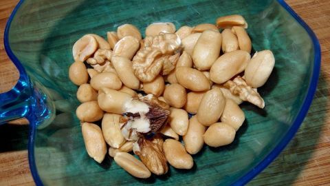 Dem Hamster Nüsse in seine Vorderhände geben und schon stopft er sich damit voll und hat die süßen Hamsterbäckchen. Eine Schale mit Erdnüssen, in der sich einige geschälte Nüsse befinden, ideal zum Hamster füttern.