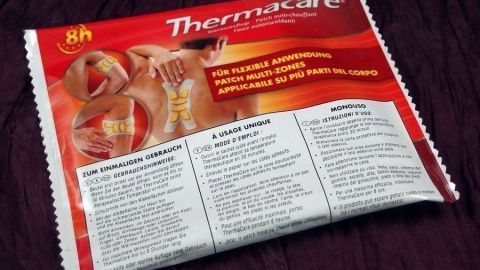 Wärmflasche von ThermaCare zeigt eine rote Verpackung, die Hinweise zur Anwendung bei Schmerzen enthält.