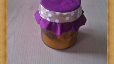 Ein Duftglas mit violettem Stoffdeckel steht auf einem Holztisch, verleiht dem Raum eine gemütliche Atmosphäre.