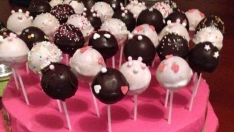 Bunte Cake Pops sind auf einem rosa Kuchenständer gesteckt und stehen zum Trocknen bereit, um als süße Leckerei serviert zu werden.