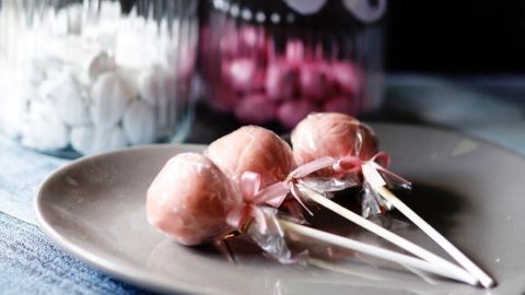 Leckere Vanille Cake Pops stehen auf einem Teller, während helle Gläser im Hintergrund Süßigkeiten enthalten.