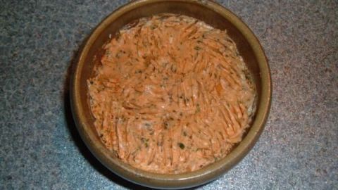 Eine Schale beherbergt selbstgemachte Kräuterbutter mit geriffelter Oberfläche, auf einer grauen Arbeitsplatte.