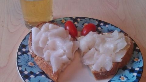 Ein Teller mit bayerischem Brot mit Rettichscheiben und Kirschtomaten, daneben steht ein Glas Bier auf einem Holztisch.
