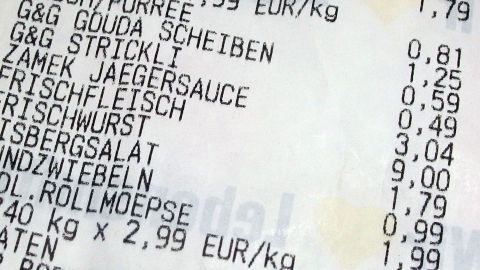 Ein Kassenbon zeigt verschiedene Lebensmittelpreise auf, während Geld gespart wird, um beim Einkaufen zu optimieren.