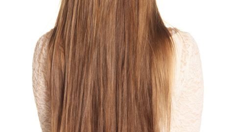 Lange, glänzende Haare fallen sanft über die Schultern einer Person, die sie von hinten zeigt, im hellen Hintergrund.