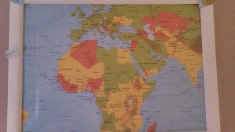 Eine Weltkarte als gerahmte Deko hängt an der Wand, verziert mit herzförmigen Notizen an den Ecken: "Canada", "Kitzbühel", "dream".