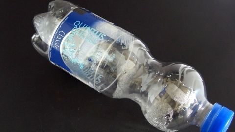 Eine Wasserflasche liegt flach auf einem Tisch, möglicherweise als kreative Methode, um Fliegen zu fangen.