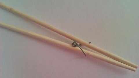 Essstäbchen mit einfacher Federmechanik liegen auf weißem Hintergrund, zeigen eine innovative Technik für Anfänger.