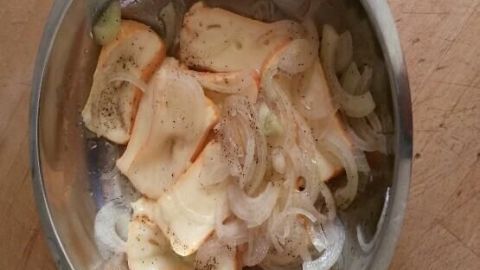 Eine silberne Schüssel enthält Limburger Käse und Zwiebeln, die zusammen vermengt werden, um eine fränkische Spezialität zu kreieren.