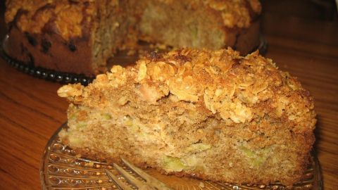 Ein Stück Rhabarber-Nuss-Torte mit einer goldbraunen Mandelkruste liegt auf einem Teller und sieht köstlich aus.
