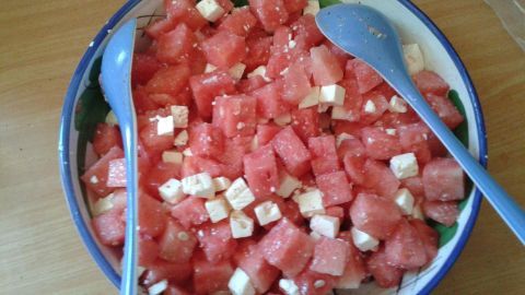 Saftige Wassermelonenwürfel liegen zusammen mit Feta in einer bunten Schüssel auf einem Holztisch, bereit zum Servieren.