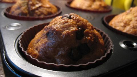 Frisch gebackene Bananen-Apfel-Muffins befinden sich in einer Muffinform, umgeben von anderen köstlichen Backwaren.