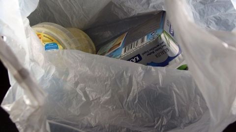 Obsttüten aus dem Supermarkt als Müllbeutel weiterverwenden. Eine durchsichtige Mülltüte enthält verschiedene Lebensmittelverpackungen, die als Abfall in einem Einkaufsumfeld zu sehen sind.
