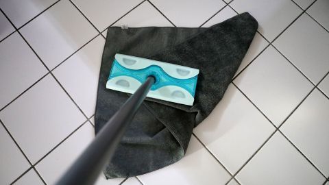 Ein Wischmopp steht auf gefliester Fläche, während er bereit ist, die Reinigung zu beginnen. Vor dem Wischen nicht fegen.