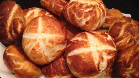 Laugenbrötchen liegen auf einem weißen Teller, gebacken bis goldbraun, in einer Küche.