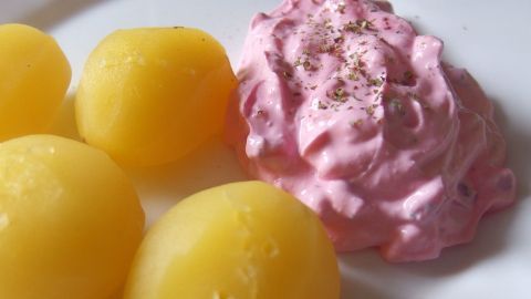 Pellkartoffeln sind auf einem Teller neben einer cremigen Rote-Bete-Quark-Mischung in leuchtendem Rosa angerichtet.