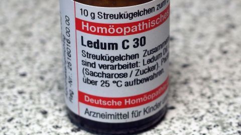 Ein kleines Fläschchen mit dem Etikett „Homöopathische“ sowie der Aufschrift „Ledum C 30“ steht auf einer grauen, strukturierten Oberfläche.