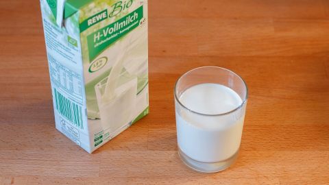 Milchkarton und Glas auf Holzoberfläche; Karton zeigt "REWE Bio H-Vollmilch" - geeignet zum Mildern von Schärfe.