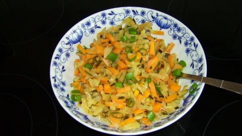 Ein bunter Zucchini-Möhren-Fenchel-Salat wird in einer dekorativen Schüssel auf einem dunklen Tisch präsentiert.