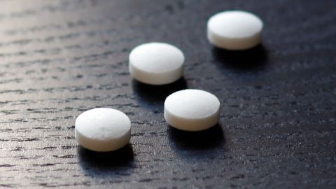 Weiße Bullrich Salz Tabletten liegen auf einer dunklen Holzfläche und warten darauf, gegen Katerbeschwerden eingenommen zu werden.