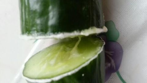 Gurke liegt in zwei Hälften geteilt auf einer Oberfläche mit Blumendekor und ist frisch geschnitten.